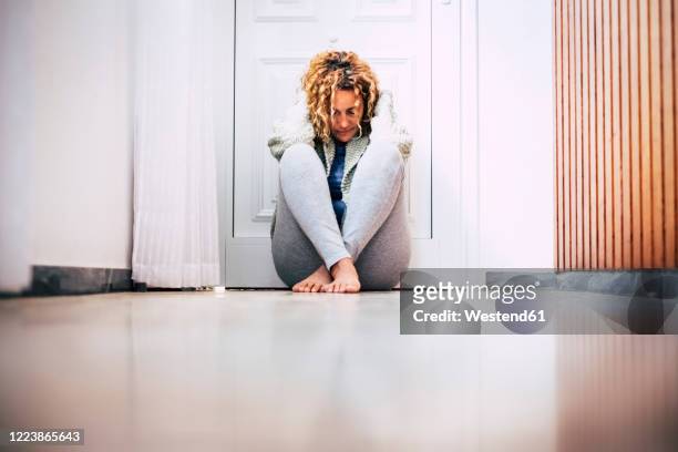 despaired woman sitting on floor in corridor in front of locked door - phobia imagens e fotografias de stock