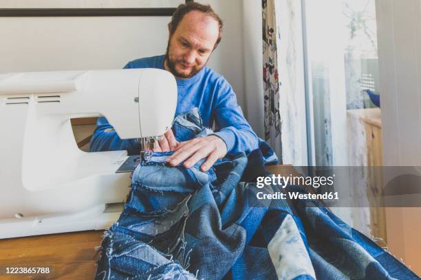 mature man sewing denim quilt at home - quilt imagens e fotografias de stock