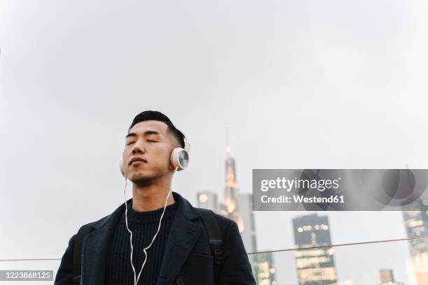 man with headphones in front of urban skyline, frankfurt, germany - headphones eyes closed stock pictures, royalty-free photos & images