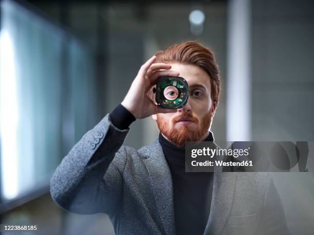 portrait of businessman looking through an object in modern office - technology innovation stock-fotos und bilder