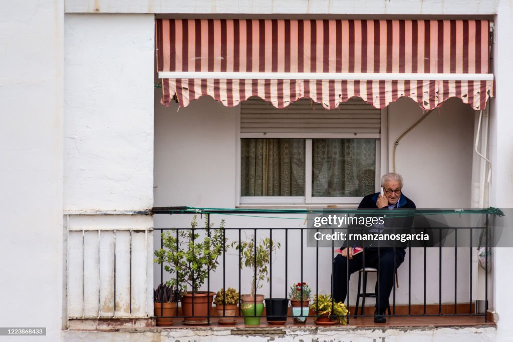 80 Jahre alter Mann telefoniert auf der Terrasse während der Gefangenschaft durch die Covid-19