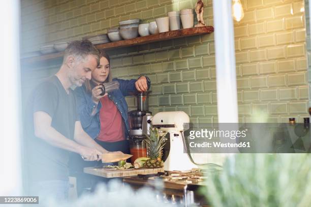 father and daughter in kitchen preparing a smoothie - mixer stock pictures, royalty-free photos & images