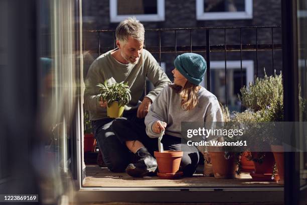 father and daughter planting together on balcony - family gardening stock-fotos und bilder