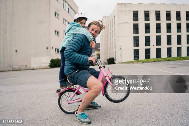 playful father with daughter on her bicycle - skimpy girls stock pictures, royalty-free photos & images
