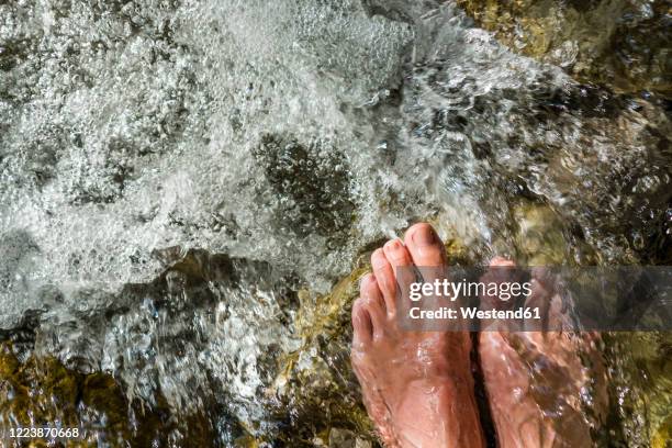 man's feet on stone in a brook - barefoot men stock-fotos und bilder