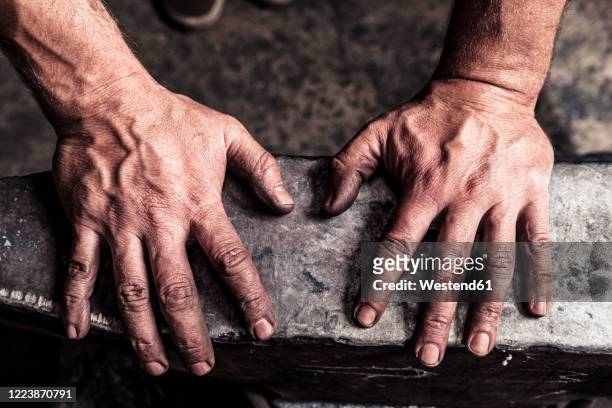 knife maker with soot-blackened hands on anvil - craft stock-fotos und bilder