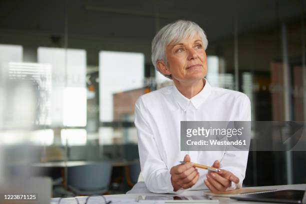 portrait of pensive senior businesswoman at desk in her office - westend 61 fotografías e imágenes de stock