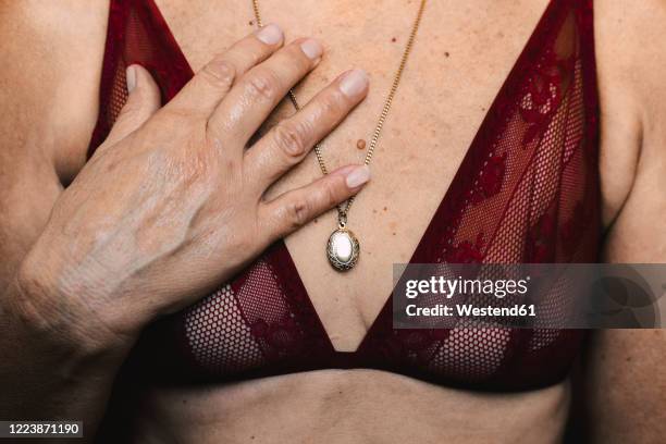 close-up of a senior woman wearing a bra and a necklace - frau brust erotisch stock-fotos und bilder
