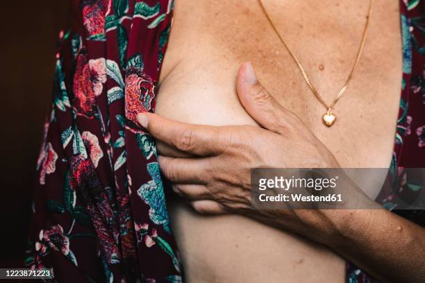 close-up of a senior woman touching her breast - chest torso stockfoto's en -beelden