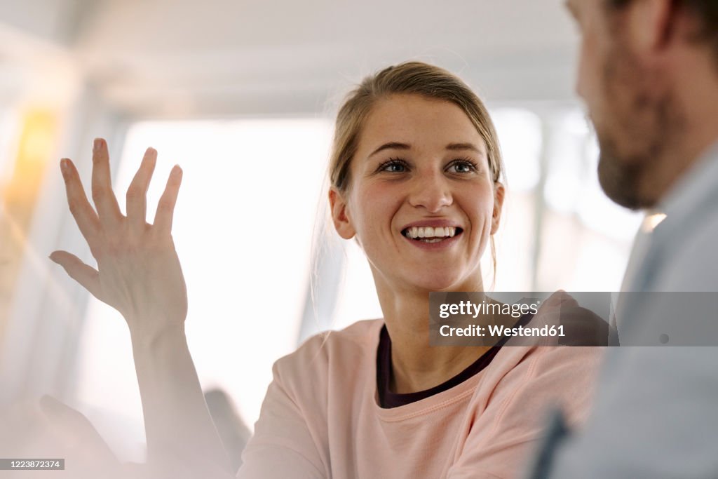 Portrait of smiling young woman talking to man