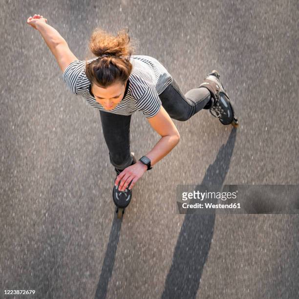 high angle view of woman inline skating on road during summer - inline skating fotografías e imágenes de stock