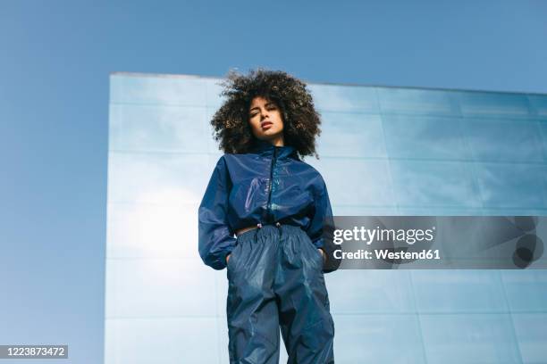 portrait of stylish young woman wearing tracksuit outdoors - low angle view imagens e fotografias de stock