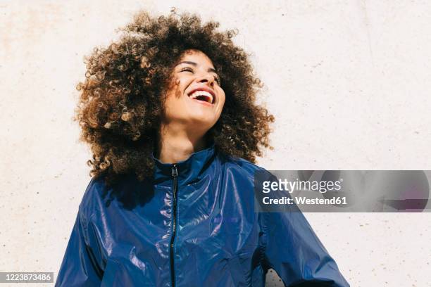 portrait of happy stylish young woman wearing tracksuit outdoors - afro frisur stock-fotos und bilder
