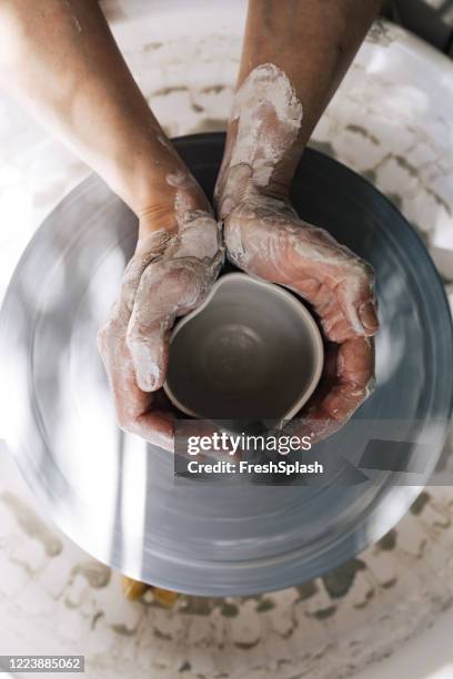 shaping clay intoa cup: a potter sculpting on a wheel - earthenware stock pictures, royalty-free photos & images