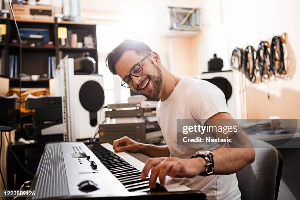 jonge hartstochtelijke mens die elektrische piano speelt - piano stockfoto's en -beelden