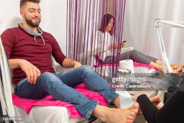 serene young man getting pedicure in beauty spa - stock photo - beautiful male feet stock pictures, royalty-free photos & images