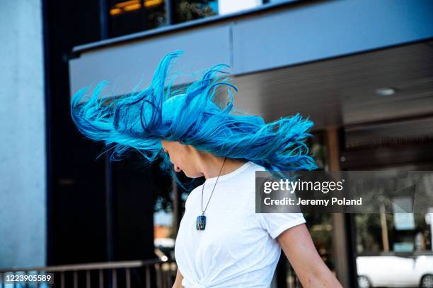 artsy low angle portrait shot of a beautiful, carefree spunky fashionable young woman with fun cute teal blue green dyed hair standing tossing her hair in the wind outdoors in the summer - teal portrait stock pictures, royalty-free photos & images
