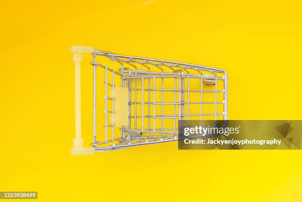 shopping trolley on yellow backgrounds - shopping trolleys stockfoto's en -beelden