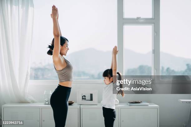 fröhliche junge asiatische mutter und kleine tochter üben und üben yoga zusammen zu hause - hong kong girl stock-fotos und bilder