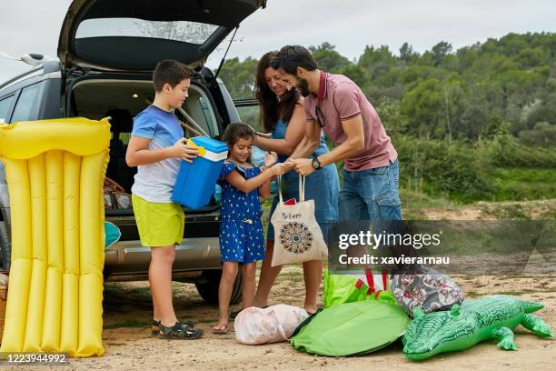 family of four unpacking suv for day at the beach - pool raft imagens e fotografias de stock