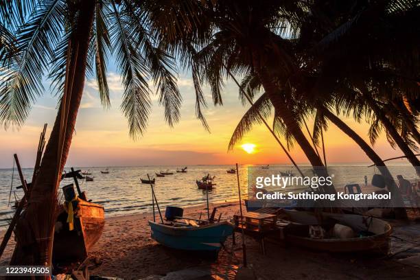 sunset over the tropical beach with coconut palm and boat at pattaya , thailand . pattaya is a paradise in thailand. silhouettes of palm trees and amazing cloudy sky on sunset at tropical beach. - goa - fotografias e filmes do acervo