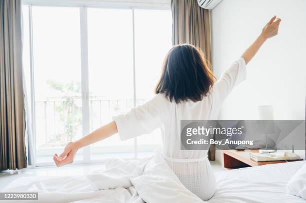 back view of young woman raised her arms for stretching in bed after wake up in the morning. - morning bed stretch stock pictures, royalty-free photos & images
