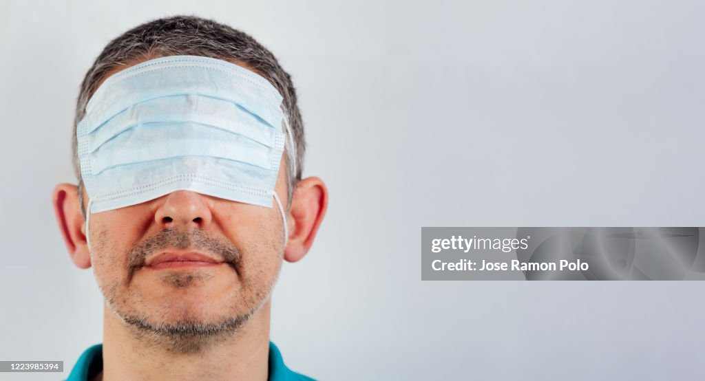 Isolated blindfolded man with surgical mask over the eyes
