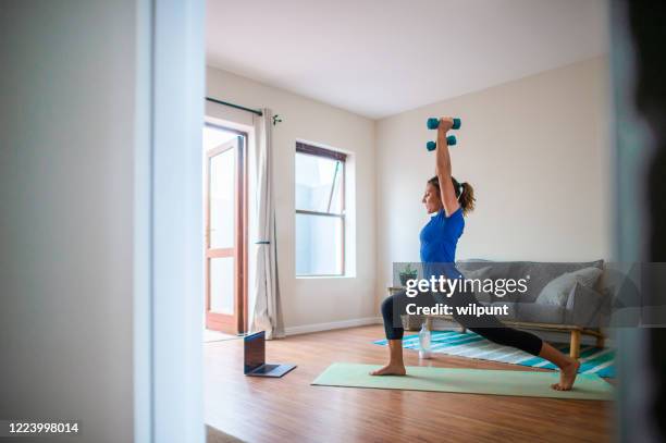 giovane ragazza che fa sessione di esercizio online a casa con manubri - home workout foto e immagini stock