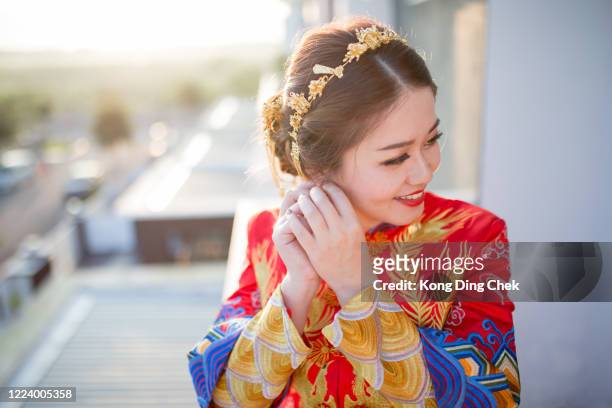 eine asiatische chinesische braut bereitet ihre hochzeit vor. sie trägt ein hochzeitskleid im chinesischen stil. - chinese wedding stock-fotos und bilder
