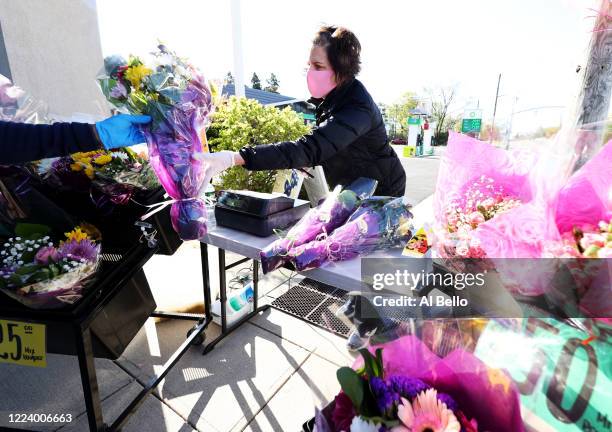 Elizabeth Mcginn works the cashier stand outside the Flowers by Voegler store on May 10, 2020 in Merrick, New York. Theresa Soto is the owner of...