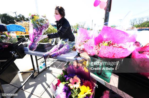Elizabeth Mcginn works the cashier stand outside the Flowers by Voegler store on May 10, 2020 in Merrick, New York. Theresa Soto is the owner of...