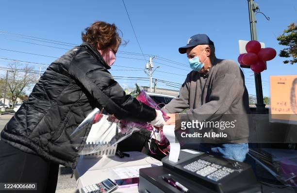 Elizabeth Mcginn works the cashier stand outside the Flowers by Voegler store on May 10, 2020 in Merrick, New York. Theresa Soto is the owner of...