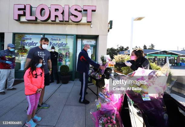 Elizabeth Mcginn works the cashier stand outside the Flowers by Voegler store on May 10, 2020 in Merrick, New York. Theresa Soto is the owner of...