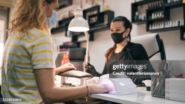 uv lamp gel polish manicure process. salon procedure. the master coats the client's nails with a varnish. - nail salon stock pictures, royalty-free photos & images