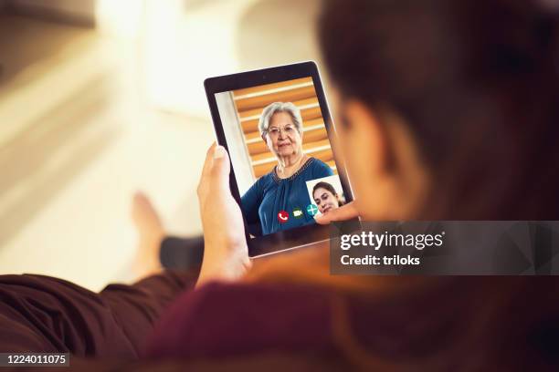 dochter die op videovraag met haar moeder spreekt die digitale tablet gebruikt - mother daughter webcam stockfoto's en -beelden