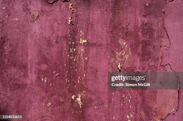 maroon paint peeling off a concrete stucco building exterior wall - burgundy stock pictures, royalty-free photos & images