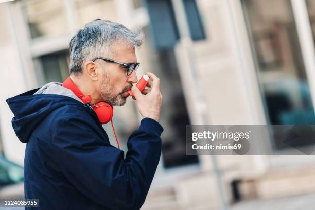 man using asthma inhaler - man inhaler stock pictures, royalty-free photos & images