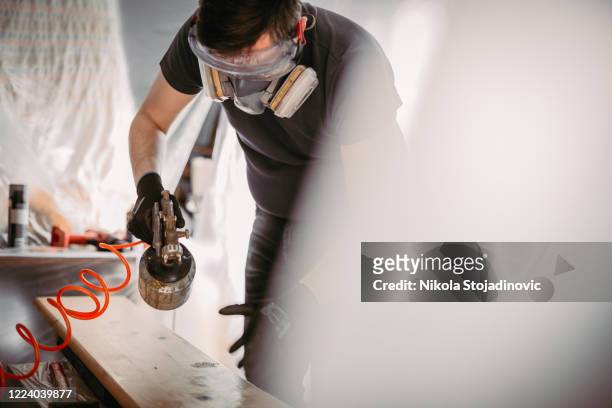 carpenter with mask using paint spray gun to painting wooden plank - spray gun stock pictures, royalty-free photos & images