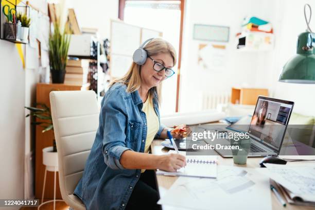 mature businesswoman working remotely and having video call with colleagues - webinars woman stock pictures, royalty-free photos & images