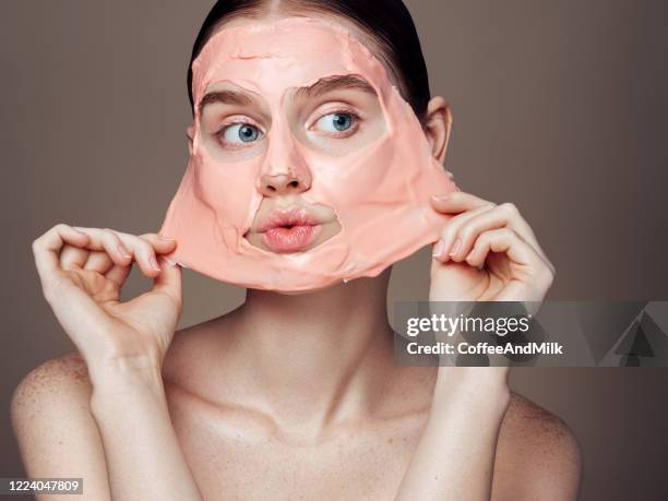 mujer quitando la máscara de la cara - masks fotografías e imágenes de stock