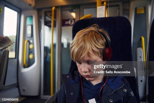 child on a train wearing headphones - train interior stock pictures, royalty-free photos & images