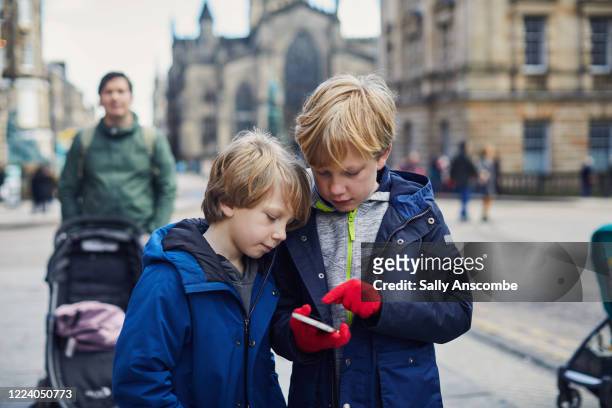 children looking at a smart phone together - edinburgh scotland stockfoto's en -beelden