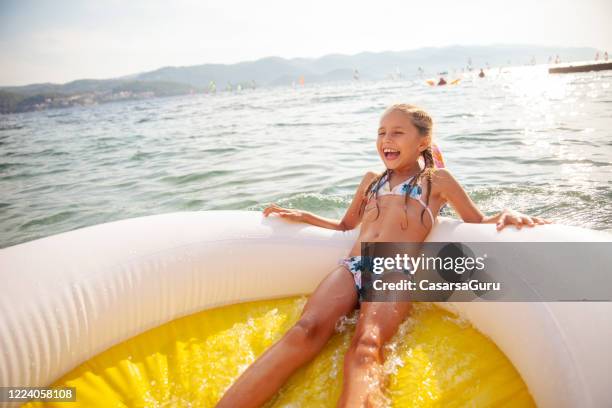 carefree little girl enjoying on pool raft in the sea on summer vacations - inflatable swimming pool stock pictures, royalty-free photos & images