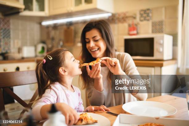 mother and daughter have fun while eating pizza - italian mother kitchen stock pictures, royalty-free photos & images