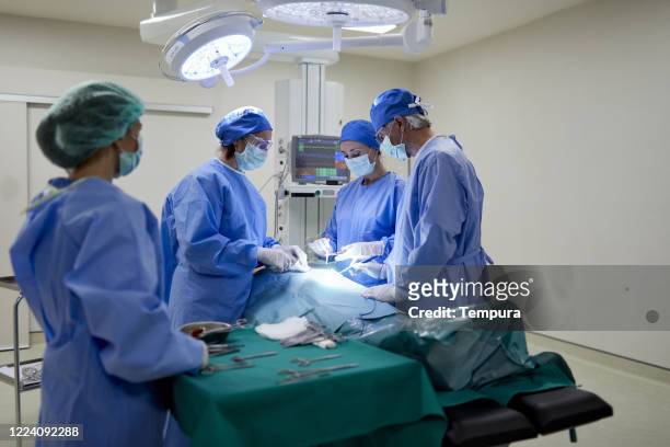 over the shoulder view of a nurse assisting a team of surgeons. - general view stock pictures, royalty-free photos & images