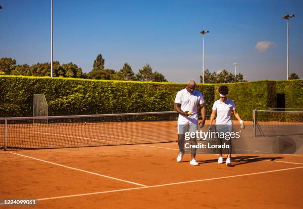 a beautiful black female tennis player on the court with her coach father - profesional amateur stock pictures, royalty-free photos & images