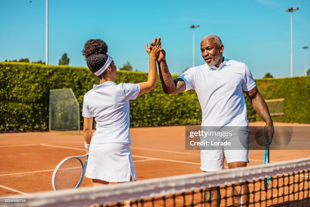 A beautiful black female tennis player on the court with her coach father