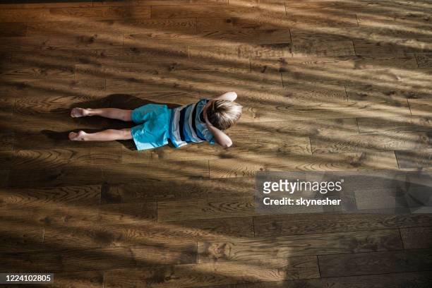 above view of a small boy exercising on parquet floor. - child yoga elevated view stock pictures, royalty-free photos & images