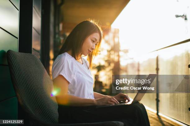 young woman working with laptop on the balcony - japanese people lesson english stock pictures, royalty-free photos & images