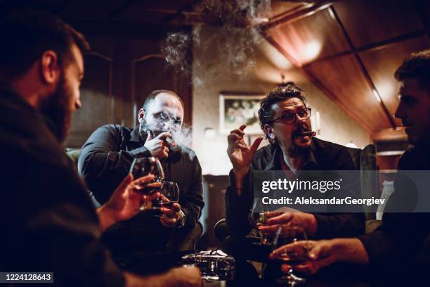 uomini ricchi che bevono buon whisky e si godono i sigari cubani - mob foto e immagini stock